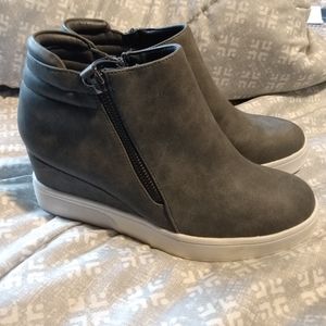 Pair of gray wedge style ankle high shoes.